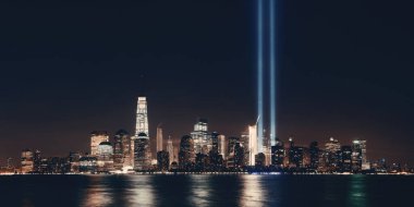New York City downtown skyline at night panorama over Hudson River and September 11 tribute light clipart