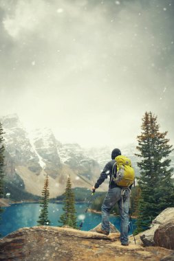 Moraine Gölü 'ndeki yürüyüşçü kar yağışlı bir günde Kanada' daki Banff Ulusal Parkı 'nın karlı tepesinde