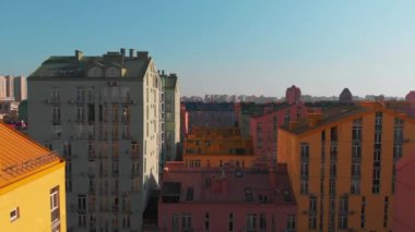 Günbatımında renkli evler üzerinde insansız hava aracı uçuşu. Comfort Town, Kiev, Ukrayna. Renkli binaları olan bir yerleşim yeri. Kamera ileri gidiyor. Hava görüntüsü, İHA video görüntüleri.