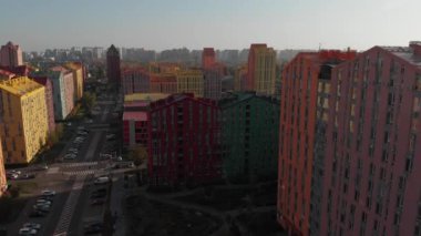 Günbatımında renkli evler üzerinde insansız hava aracı uçuşu. Comfort Town, Kiev, Ukrayna. Renkli binaları olan bir yerleşim yeri. Kamera ileri gidiyor. Hava görüntüsü, İHA video görüntüleri.