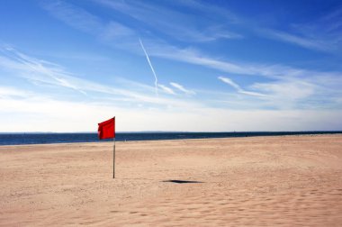Yüzmek tehlikelidir ve yasaktır. Güneşli bir günde Coney Adası, New York 'ta rüzgarda dalgalanan kırmızı uyarı bayrağı..
