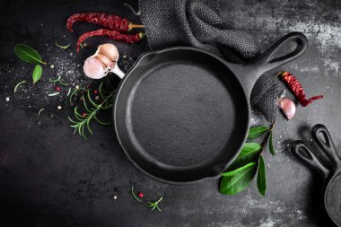 cast iron pan and spices on black metal culinary background clipart