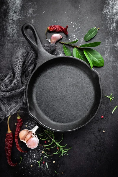 Cast iron pan and spices on black metal culinary background — ストック写真