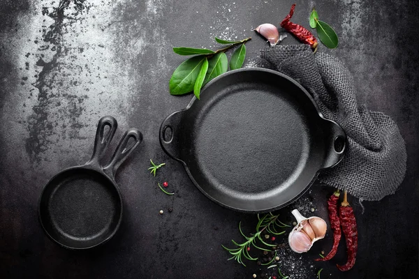 Cast iron pan and spices on black metal culinary background — ストック写真