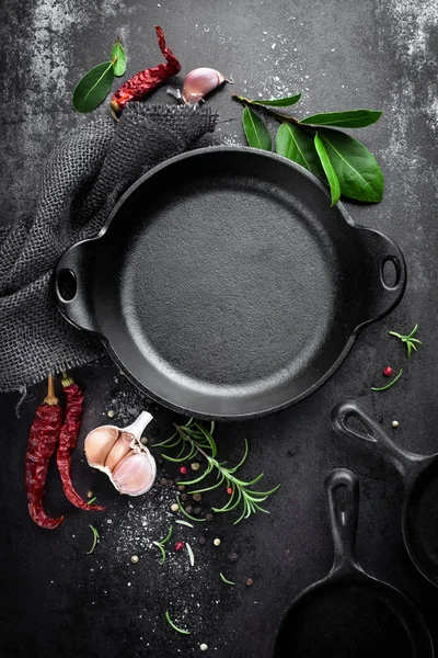 Panela de ferro fundido e especiarias em fundo culinário de metal preto — Fotografia de Stock