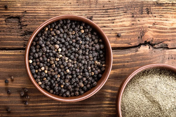 Black pepper on wooden background — Stock Photo, Image