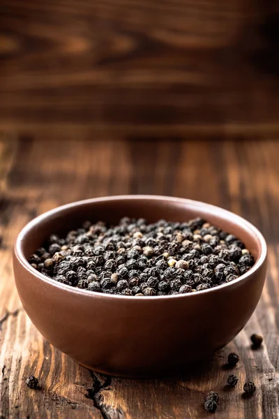 Black pepper on wooden background — Stock Photo, Image