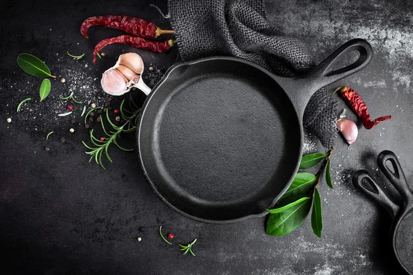 Gusseiserne Pfanne und Gewürze auf schwarzem Metall kulinarischen Hintergrund — Stockfoto