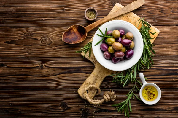 Rozemarijn, olijven, olijfolie op houten achtergrond — Stockfoto