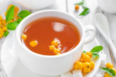 Taze sıcak bitkisel alıç çay ahşap arka plan üzerinde beyaz bir fincan taze çilek ile