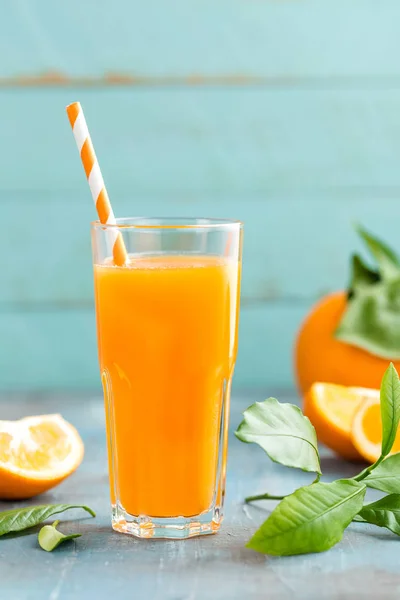 Jus d'orange en verre et fruits frais avec feuilles sur fond bois — Photo