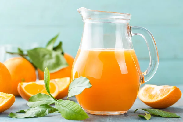 Zumo de naranja en vaso y frutas frescas con hojas sobre fondo de madera —  Fotos de Stock