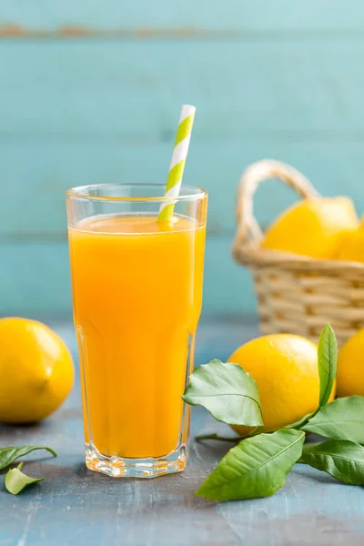 Лимонний сік у склі та свіжі фрукти з листям на дерев'яному фоні — стокове фото