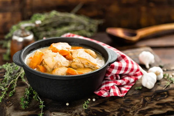 Vlees gestoofd met wortelen in de saus en kruiden in gietijzer pan op donkere houten rustieke achtergrond — Stockfoto