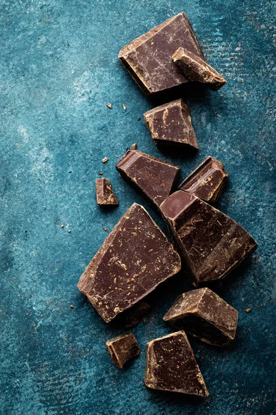 Dark chocolate pieces crushed on a dark background, view from above — Stock Photo, Image