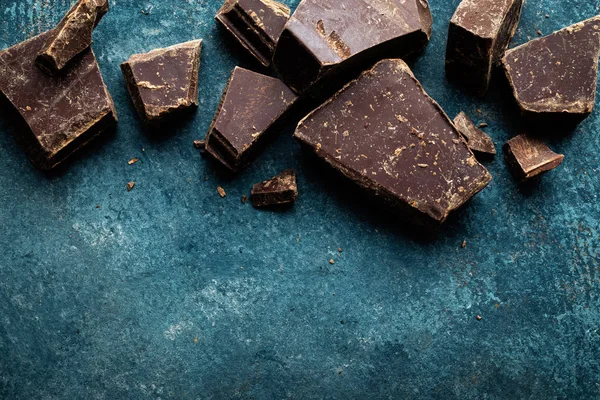 Dark chocolate pieces crushed on a dark background, view from above — Stock Photo, Image
