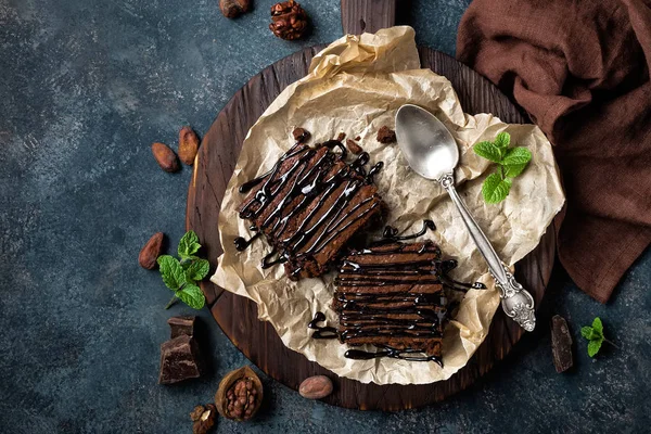 Pastel de brownie de chocolate, postre con nueces sobre fondo oscuro, directamente encima, acostado plano — Foto de Stock