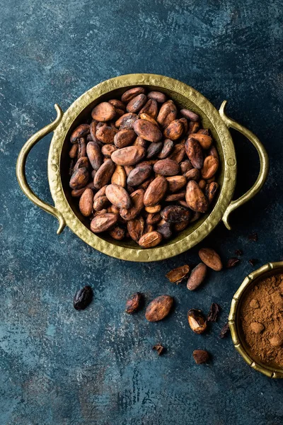 Frijoles de cacao y polvo sobre fondo oscuro, vista superior, espacio para copiar, disposición plana — Foto de Stock