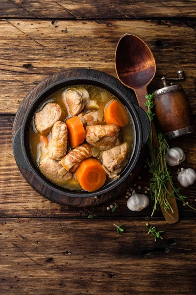 Carne tocană cu morcovi în sos și condimente în oală de fontă pe fundal rustic din lemn închis — Fotografie, imagine de stoc