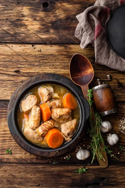 Kött kokt med morötter i såsen och kryddor i gjutjärn gryta på mörk trä rustik bakgrund — Stockfoto