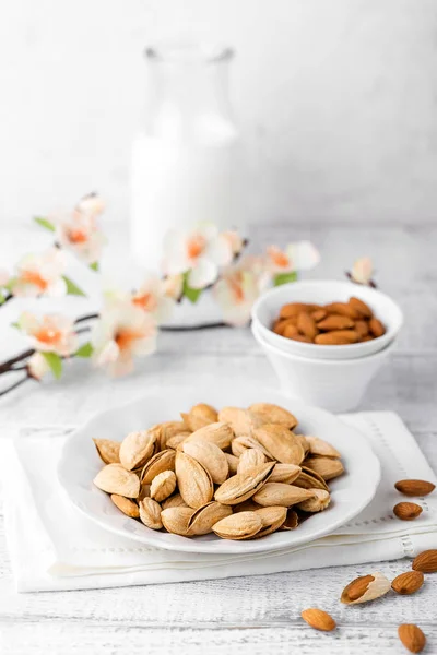 Миндальные орехи и молоко на белом фоне — стоковое фото