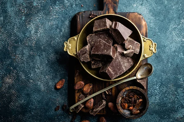 Dark chocolate pieces crushed and cocoa beans, culinary background, top view — Stock Photo, Image