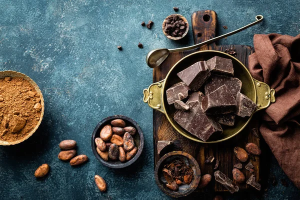 Piezas de chocolate negro triturado y granos de cacao, fondo culinario, vista superior — Foto de Stock