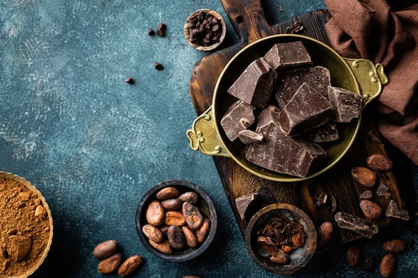 Pedaços de chocolate escuro esmagado e grãos de cacau, fundo culinário, vista superior — Fotografia de Stock