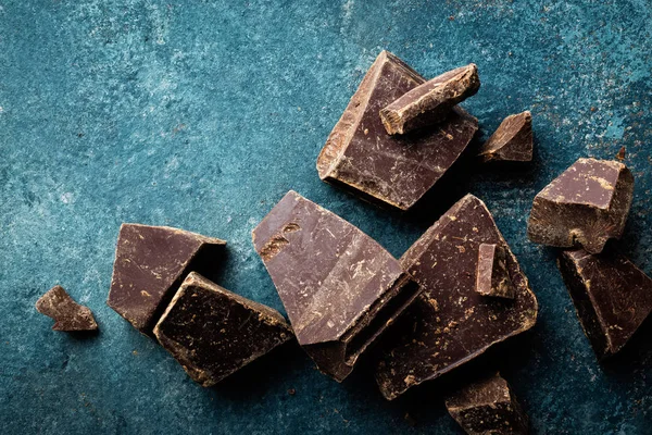Trozos de chocolate negro aplastados sobre un fondo oscuro — Foto de Stock