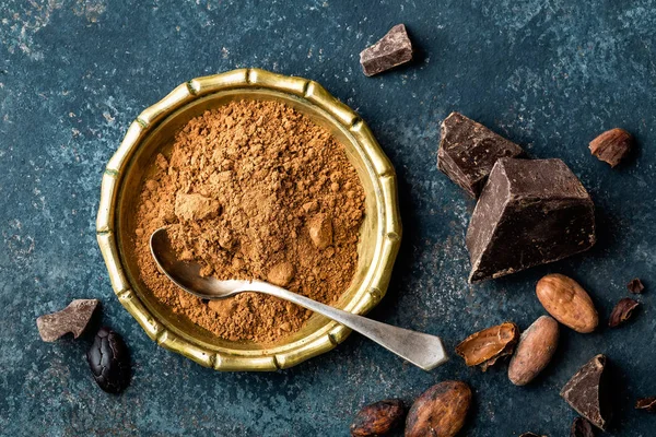 Kakaopulver, Bohnen und dunkle Schokoladenstücke zerkleinert, kulinarischer Hintergrund, Draufsicht — Stockfoto