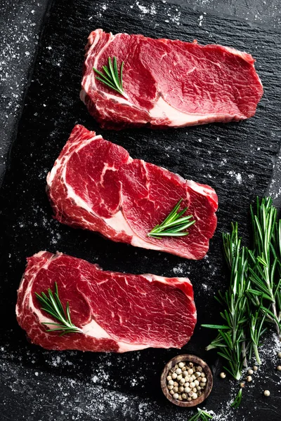 Obearbetat kött, nötkött biff på svart bakgrund, ovanifrån — Stockfoto
