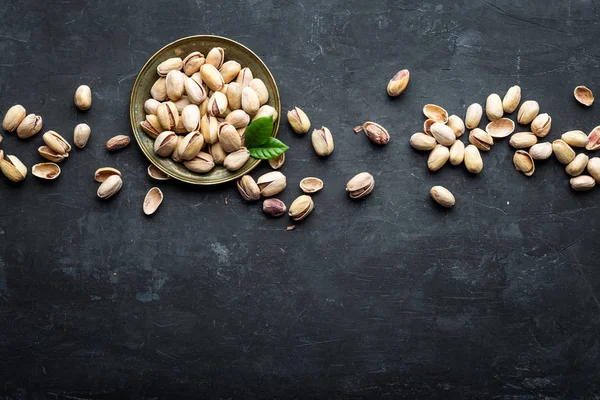 Pistaschnötter på mörk bakgrund, ovanifrån, hälsosamt mellanmål — Stockfoto