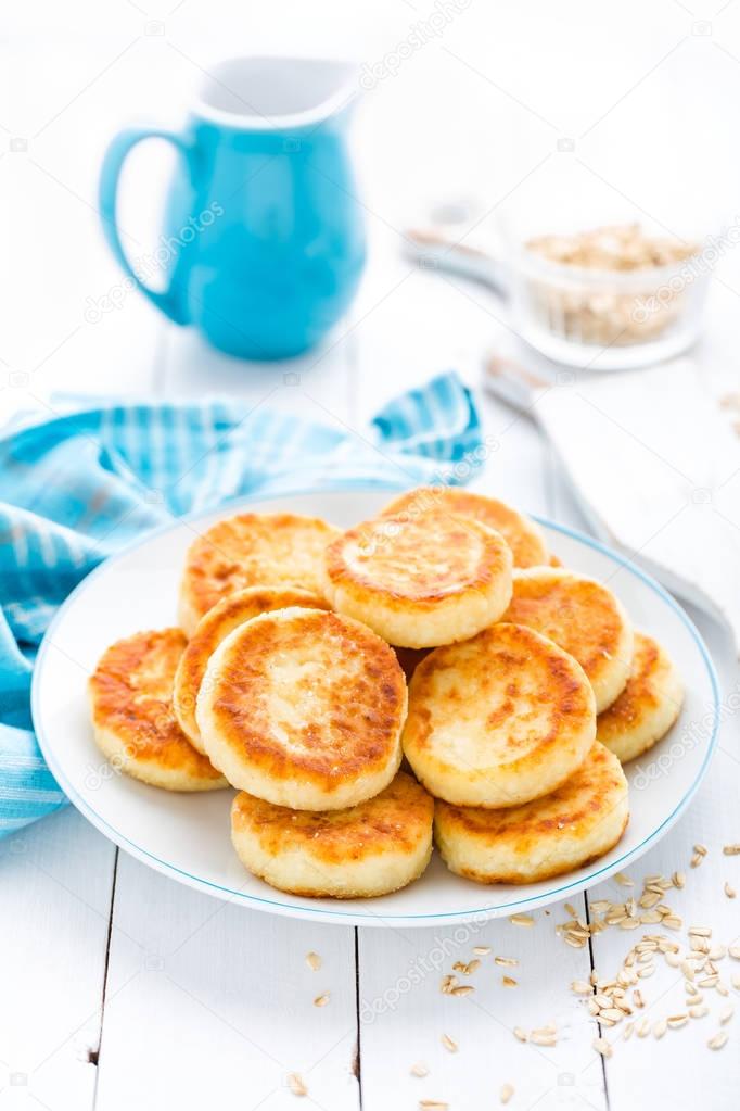 Cottage cheese pancakes with oats, syrniki on white rustic background