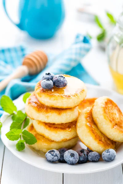 Crêpes au fromage cottage avec miel et myrtille sur fond blanc, petit déjeuner ou déjeuner — Photo