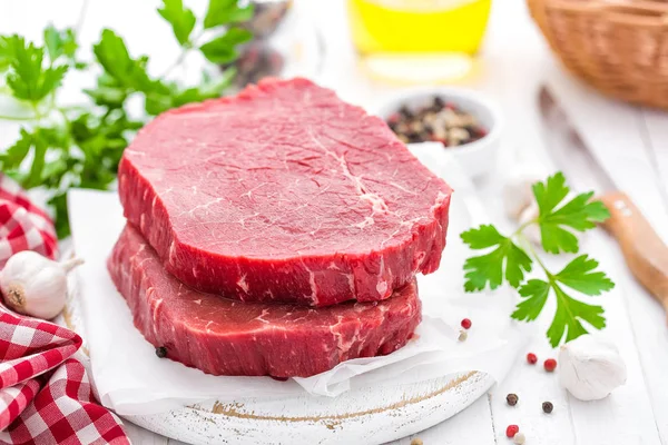 Raw, uncooked beef meat steaks on white wooden background — Stock Photo, Image