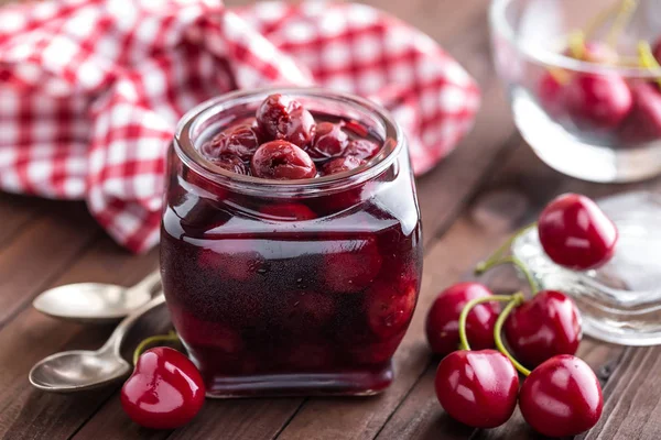 Berries cherry with syrup in a glass jar. Canned fruit