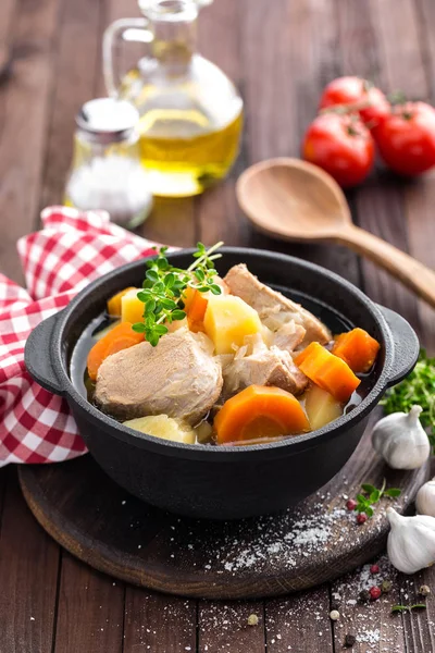 Carne estofada con zanahorias y patatas en salsa sobre fondo rústico de madera — Foto de Stock