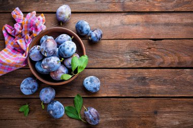 Ahşap rustik arka plan, üstten görünüm üzerinde yeşil yaprakları ile taze Erik