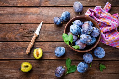 Ahşap rustik arka plan, üstten görünüm üzerinde yeşil yaprakları ile taze Erik