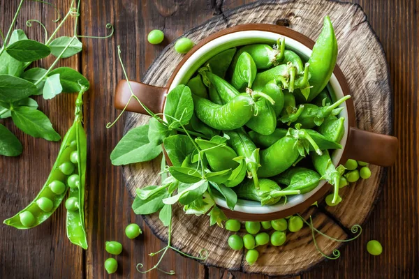 Koyu ahşap rustik arka plan üzerinde taze yeşil bezelye