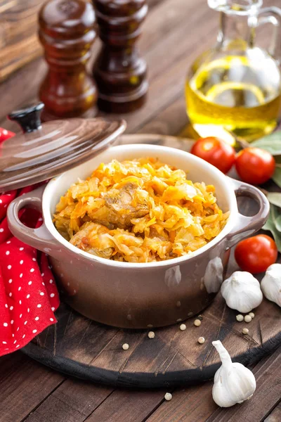 Stewed cabbage with meat on dark rustic wooden background — Stock Photo, Image