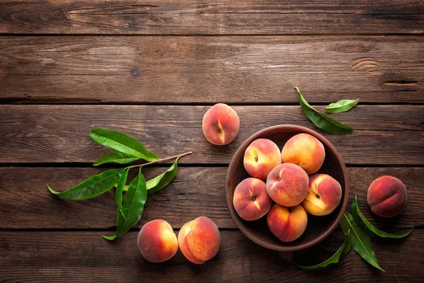 Fresh juicy peaches with leaves on dark wooden rustic background — Stock Photo, Image