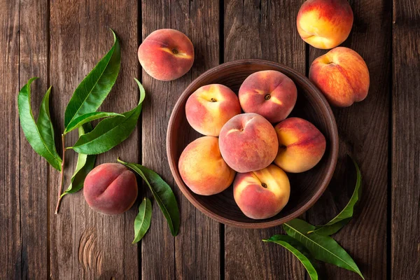 Fresh juicy peaches with leaves on dark wooden rustic background — Stock Photo, Image