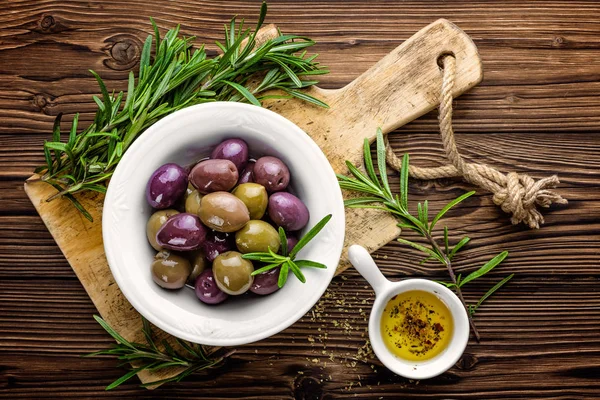 Aceitunas en tazón con aceite de oliva sobre fondo rústico de madera oscura, por encima de la vista; cocina italiana — Foto de Stock