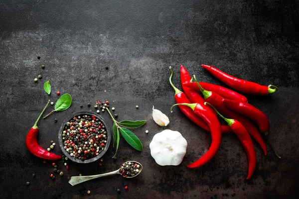 Red hot chili pepeprs and peppercorns on black metal background, top view — Stock Photo, Image