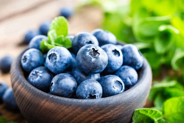 在木制桌子上的碗里放新鲜蓝莓 — 图库照片