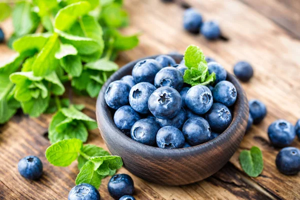 Fresh blueberries in bowl on wooden table — Stock Photo, Image
