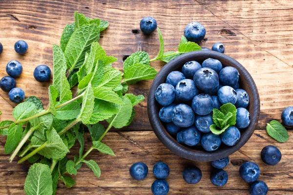 Färska blåbär i skål på träbord — Stockfoto