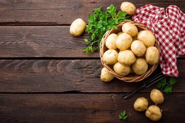 Raw potato in basket on wooden table, top view — Stock Photo, Image