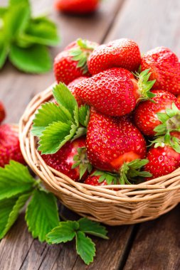 Taze çilek sepeti ahşap rustik masa, closeup üzerinde. Lezzetli, sulu, kırmızı çilek. Sağlıklı beslenme.